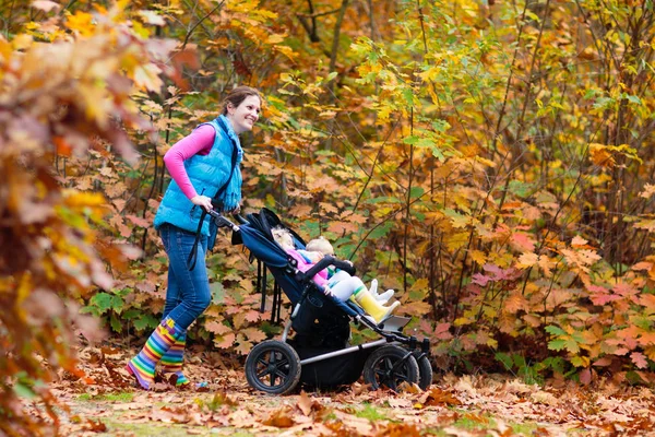 Caminhadas em família com carrinho no parque de outono — Fotografia de Stock