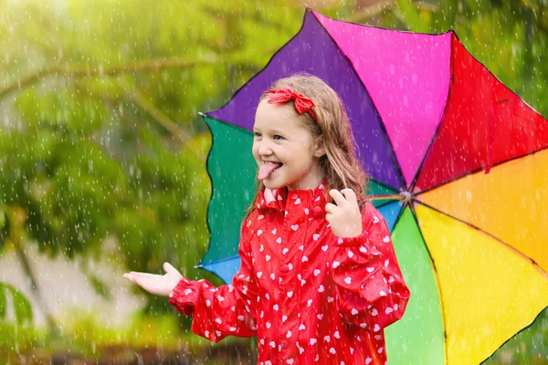 Kind mit Regenschirm spielt im Sommerregen. — Stockfoto