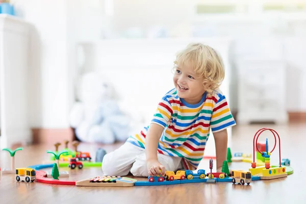 Дети играют на деревянной железной дороге. Ребёнок с игрушечным поездом . — стоковое фото