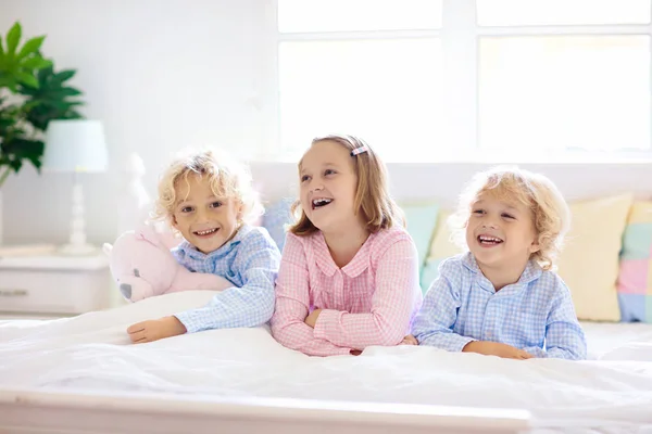 Os miúdos brincam na cama. Crianças em casa . — Fotografia de Stock