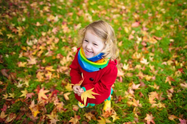 Klein meisje spelen met Maple Leaf in de herfst — Stockfoto