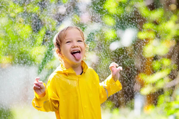 Ребенок играет под дождем. Мальчик с зонтиком . — стоковое фото