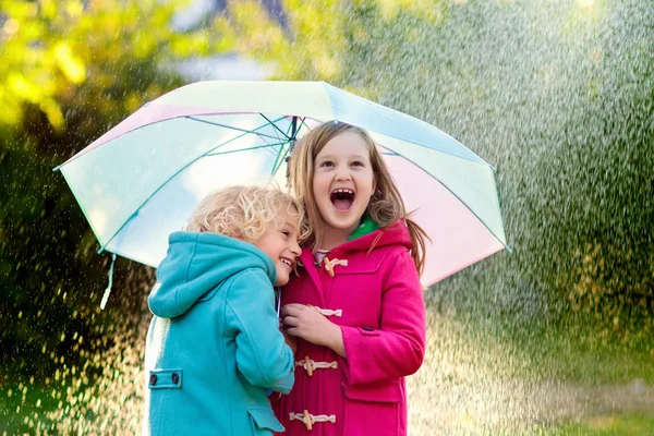 Dzieci z parasolem grając w jesiennym deszczu deszcz. — Zdjęcie stockowe