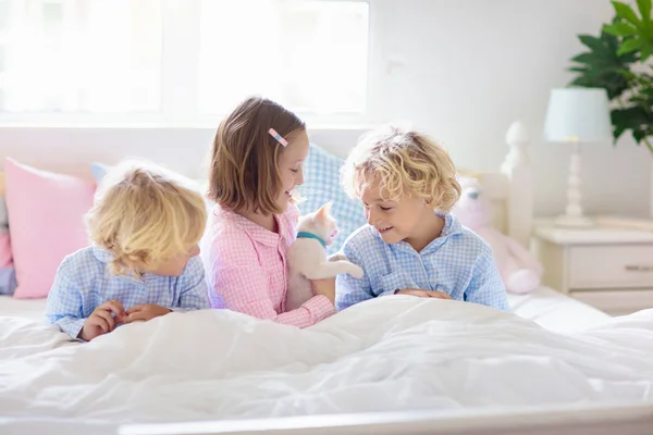 Kinder spielen mit Katzenbabys. Kind und Kätzchen im Bett. — Stockfoto