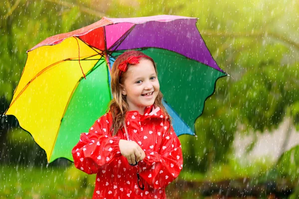 Kind mit Regenschirm spielt im Sommerregen. — Stockfoto