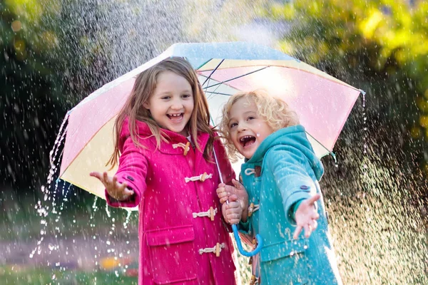 Niños con paraguas jugando en la lluvia de otoño . — Foto de Stock