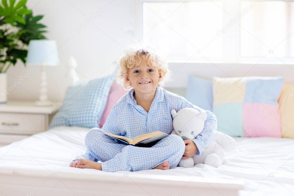 Child reading book in bed. Kids read in bedroom. 