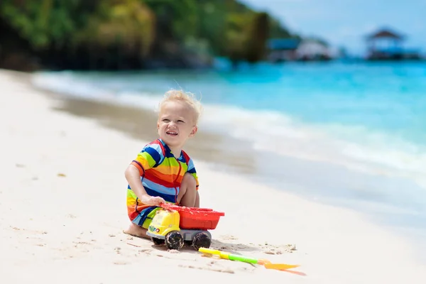 Dzieci grają na tropikalnej plaży. Zabawki do piasku i wody. — Zdjęcie stockowe