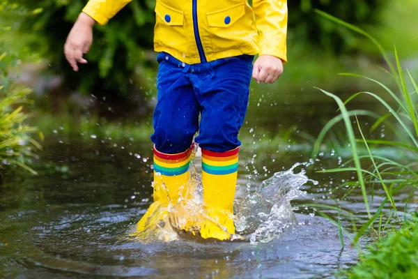 Kids in puddle in autumn rain. Waterproof wear