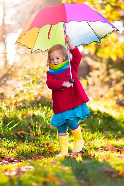 Sonbahar yağmurunda şemsiye oynayan çocuk. — Stok fotoğraf