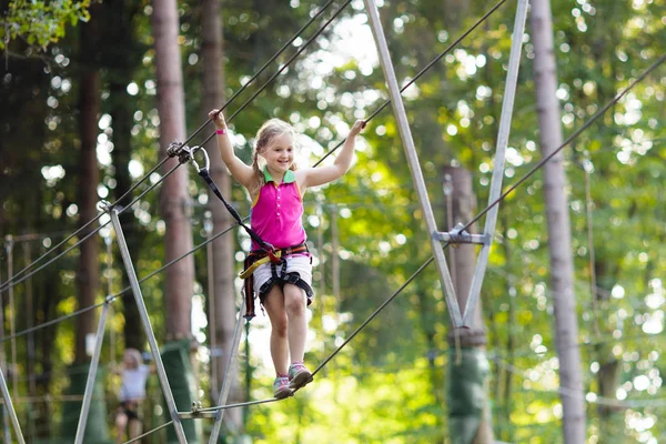 Child in adventure park. Kids climbing rope trail.