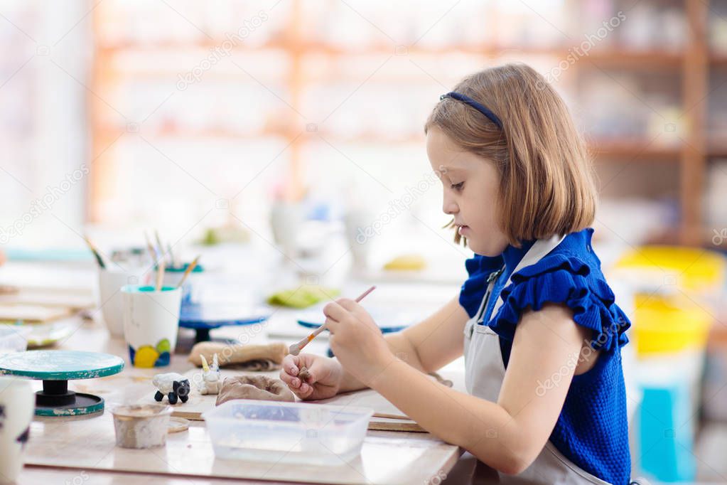 Child at pottery wheel. Kids arts and crafts class