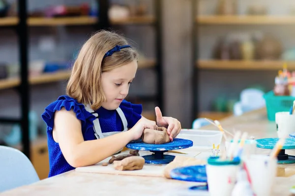 Child at pottery wheel. Kids arts and crafts class