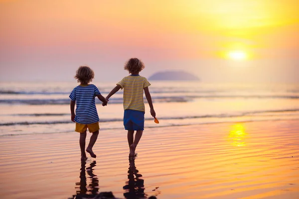 Niño jugando en la playa del océano. Niño al atardecer mar . —  Fotos de Stock