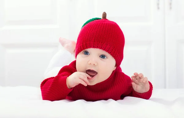 Baby in apple hat. Kid on bed. Child at home. — Stock Photo, Image