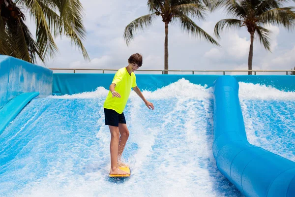 Хлопчик-підліток серфінг у симуляторі пляжної хвилі — стокове фото