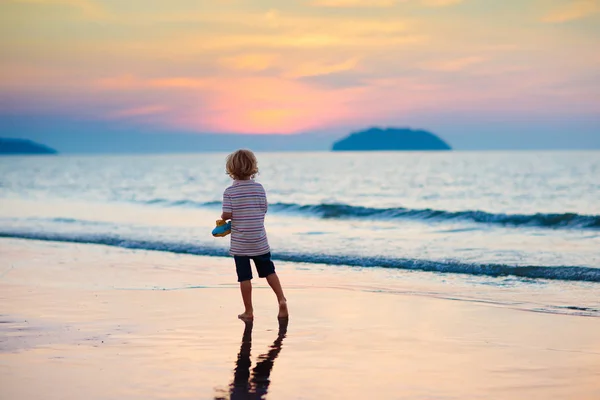 海のビーチで遊ぶ子。サンセットの海を子供します。. — ストック写真