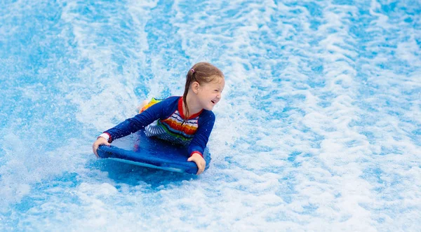 Маленька дівчинка, що серфінгує в симуляторі хвиль на пляжі — стокове фото