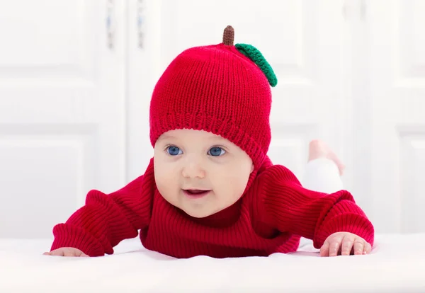Baby in apple hat. Kid on bed. Child at home. — Stock Photo, Image
