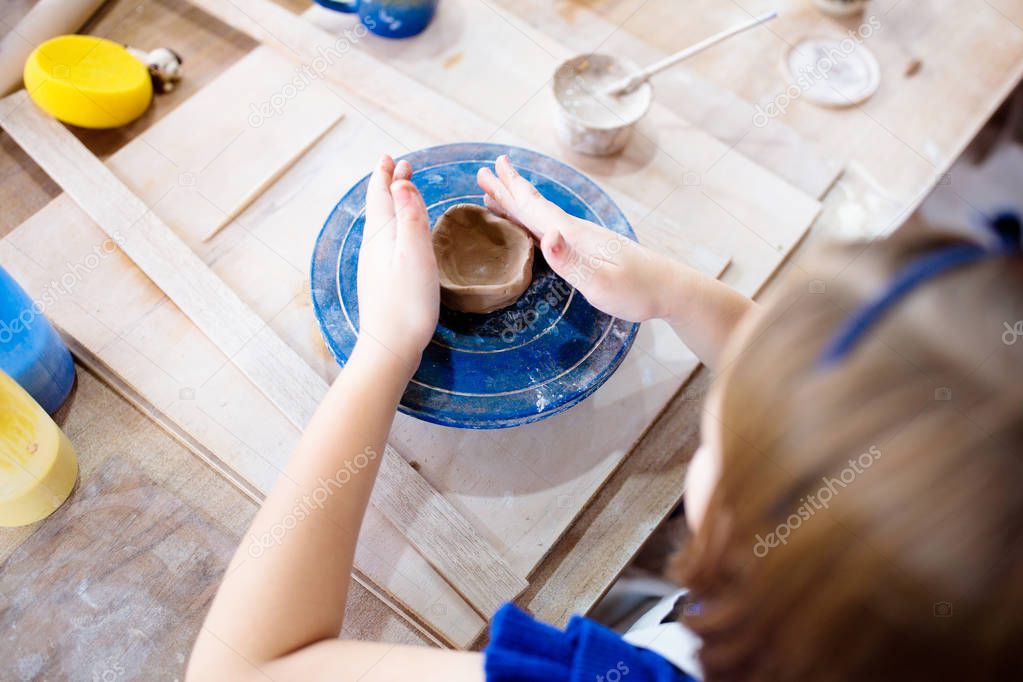 Child at pottery wheel. Kids arts and crafts class