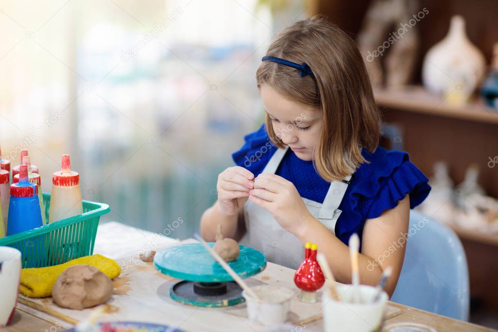 Child at pottery wheel. Kids arts and crafts class