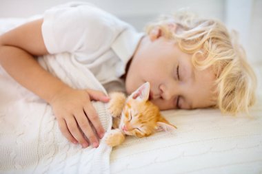 Yavru çocuk kedi yavrusuyla yatıyor. Çocuk ve kedi.