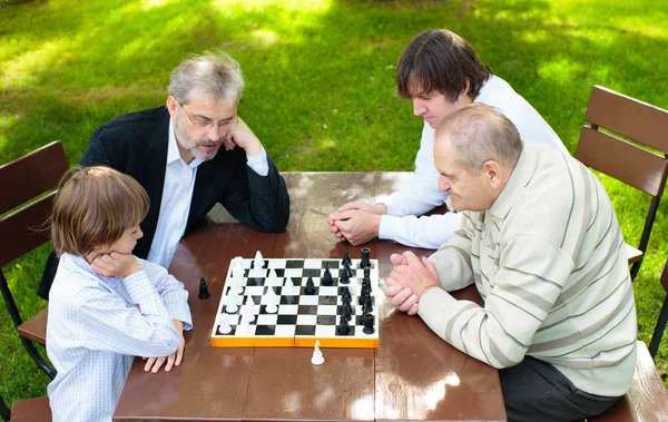 Grand-père, père et enfants jouant aux échecs . — Photo