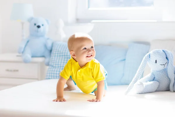 Baby boy playing on bed in sunny nursery — Stock Photo, Image