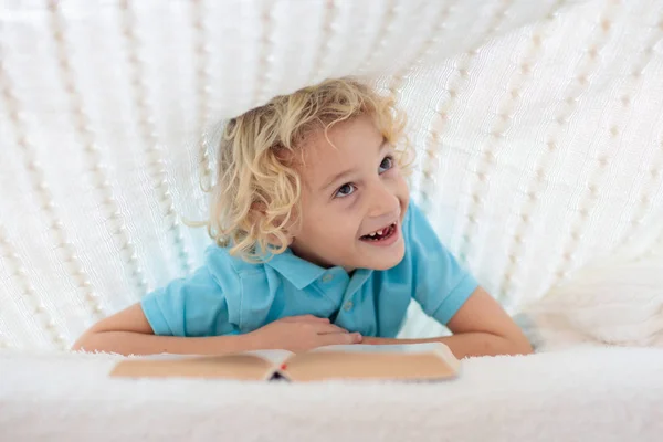 Libro de lectura infantil en la cama. Niños leen libros . — Foto de Stock