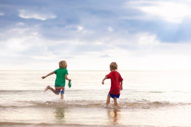 Çocuklar tropik sahilde oynar. Kum ve su oyuncak.