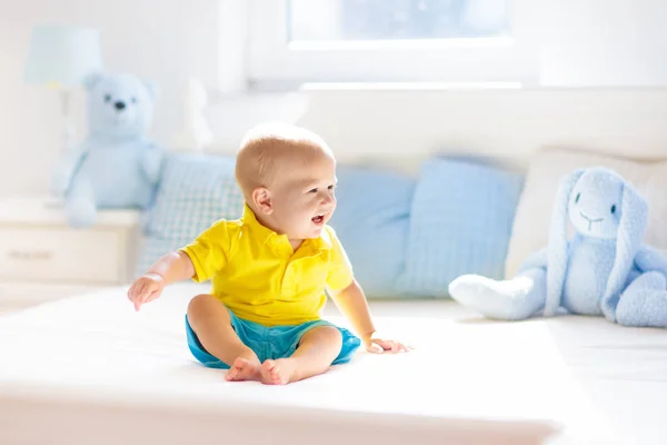 Junge spielt auf Bett in sonnigem Kinderzimmer — Stockfoto