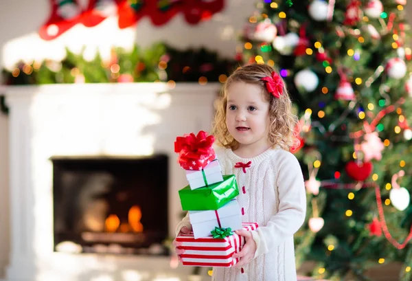 Meisje openen Kerst presenteert op haard — Stockfoto