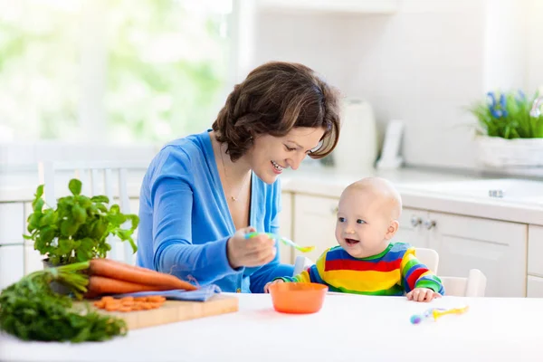 Mother feeding baby first solid food — Stock Photo, Image