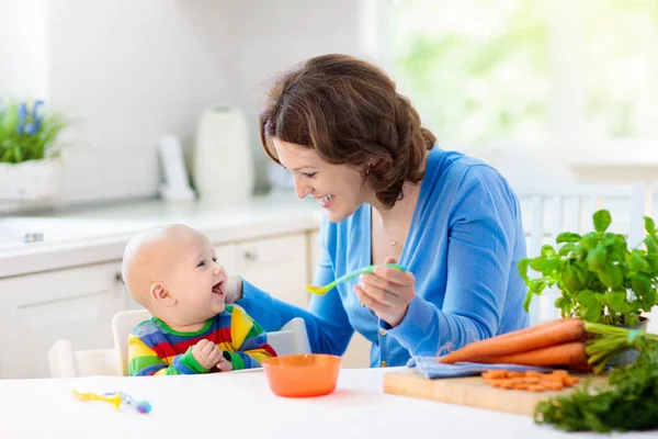 Mother feeding baby first solid food — Stock Photo, Image