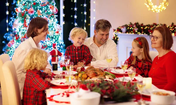 ツリーでクリスマスディナーを持っている子供たちと家族 — ストック写真