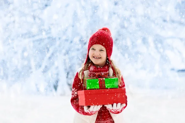 Kind mit Weihnachtsgeschenk im Schnee. Geschenke für Kinder — Stockfoto