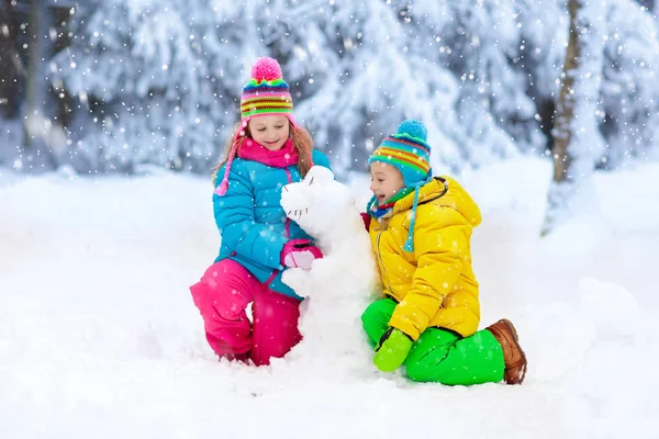 Παιδιά που φτιάχνουν χειμερινό χιονάνθρωπο. Τα παιδιά παίζουν στο χιόνι. — Φωτογραφία Αρχείου