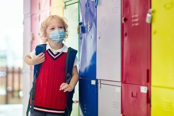 Child wearing face mask during corona virus and flu outbreak. Disease and illness protection for kids. Surgical masks for coronavirus prevention. School kid coughing. Little boy going to school.
