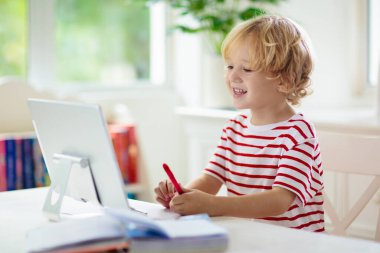 Çevrimiçi uzaktan öğrenme. Bilgisayarlı okul çocukları öğretmen ve sınıf grubuyla görüntülü konuşma yapıyorlar. Çocuk evden ders çalışıyor. Karantina ve koronavirüs salgını sırasında evde eğitim.