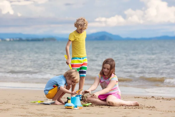 孩子们在热带海滩上玩耍 一个拿着铲子和铲子的小男孩在海滨 家庭暑假 孩子们在建造沙堡水和沙子对孩子们来说很有趣 孩子们玩 在海滨建造城堡 — 图库照片