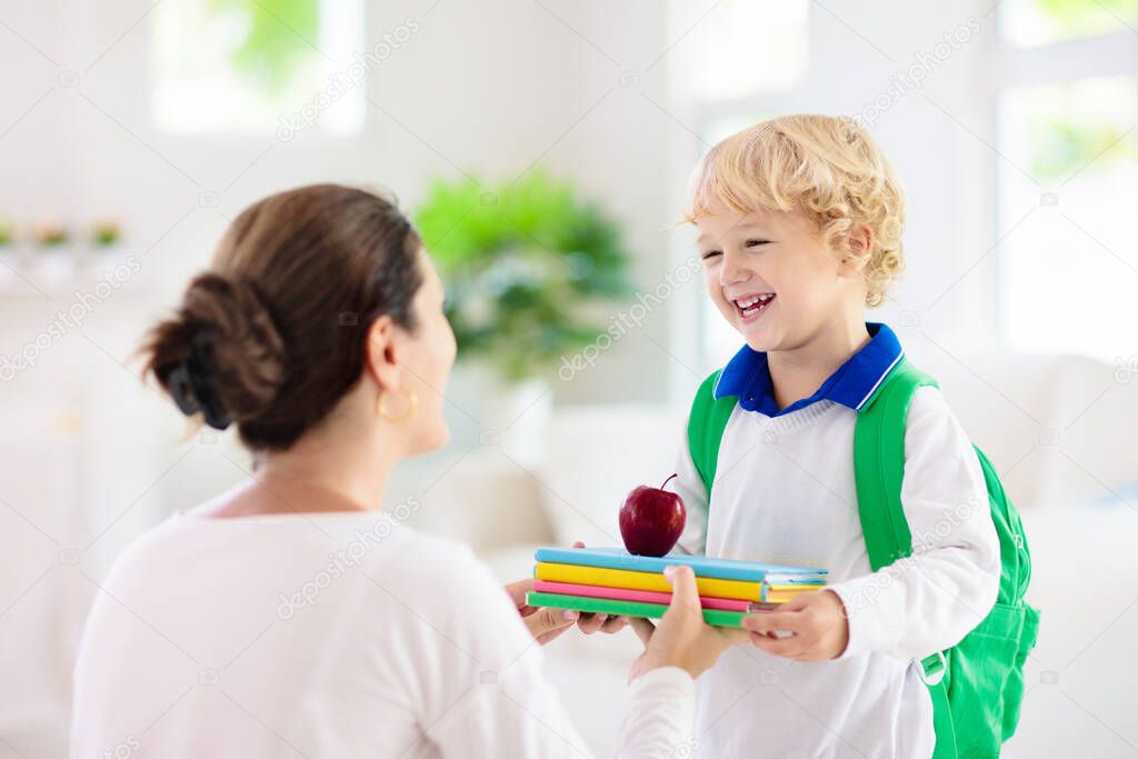 Child going back to school. Mother and kid getting ready for first school day after vacation. Little boy and mom going to kindergarten or preschool. Student packing books, apple and lunch in backpack.
