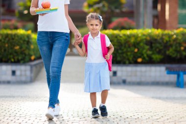 Anne ve çocuklar okuldan sonra. Anaokulundan ya da anaokulundan sonra çocukları alan genç bir anne. Öğrencileri toplayın. Oğlan ve kız okul bahçesinde ailelerine koşuyorlar..