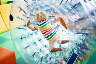 Çocuk tekerlekli sandalyede renkli trambolinde zıplıyor. Çocuklar anaokulu doğum günü partisinde şişme şatoya atlarlar. Küçük çocuklar için etkinlik ve oyun merkezi. Küçük kız oynuyor.