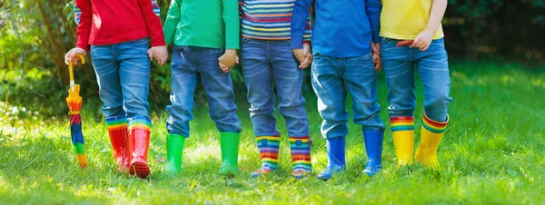 雨のブーツの子供たち カラフルなゴムブーツや秋のジャケットで幼稚園の子供たちのグループ 雨の秋のための履物 子供や赤ちゃんのための足の摩耗 ウェリーの幼児 レインボーガンブーツ キッドファッション — ストック写真