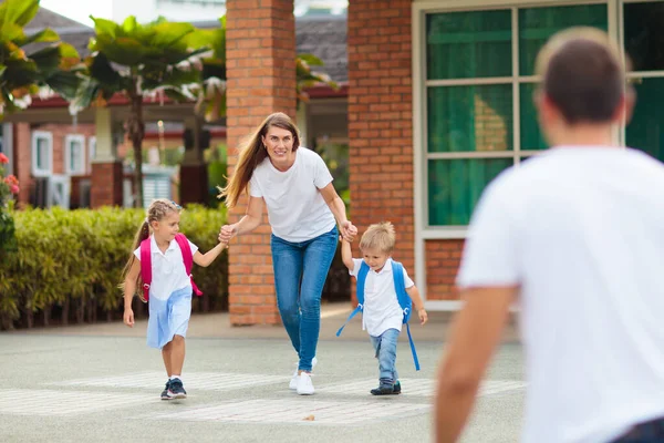 放課後の母親と子供たち 幼稚園や幼稚園でのレッスンの後に子供を拾う若いお母さん 生徒を拾え 学校の庭で親のところに走っている男の子と女の子 — ストック写真