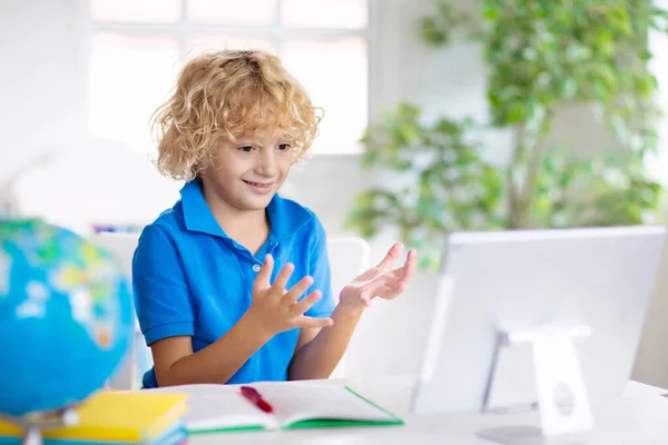 Online remote learning. School kids with computer having video conference chat with teacher and class group. Child studying from home. Homeschooling during quarantine and coronavirus outbreak.