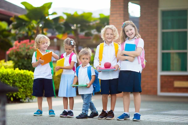 子供は学校に行く 初日は男の子と女の子が本や鉛筆を持っています 子供たちは学校に戻ることを楽しみにしていました 休暇後のクラスの開始 学校の庭でリンゴを食べる子供たち — ストック写真