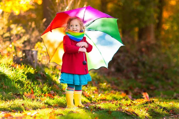 雨の中で遊んでいる子供 傘やレインブーツを着た子供たちは 豪雨の中屋外で遊ぶ 泥だらけの水たまりに飛び込む少女 子供たちは雨の秋の天気で楽しい 嵐の中を走る子供 — ストック写真