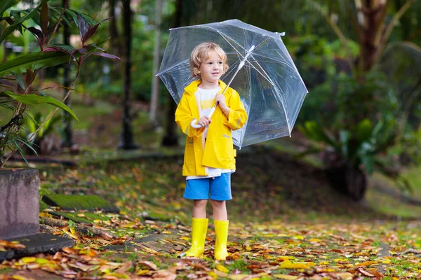 秋の雨の中で遊ぶ子供 傘を持ってる子供 秋の季節に公園を走る少年 どんな天気でも子供のための屋外の楽しみ 子供のための雨防水摩耗 ブーツやジャケット — ストック写真