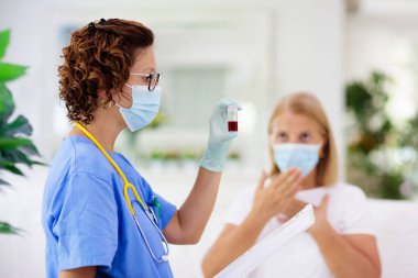 Doktor maske takan hasta hastayı muayene ediyor. Test ve tarama için sağlık kliniğindeki hasta kadın. Evde virüs tedavisi. Koronavirüs salgını. Covid-19 salgını. Kadın öksürüyor, göğsü ağrıyor..